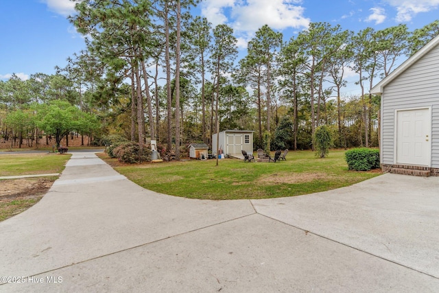 view of yard featuring an outbuilding, concrete driveway, and a storage unit
