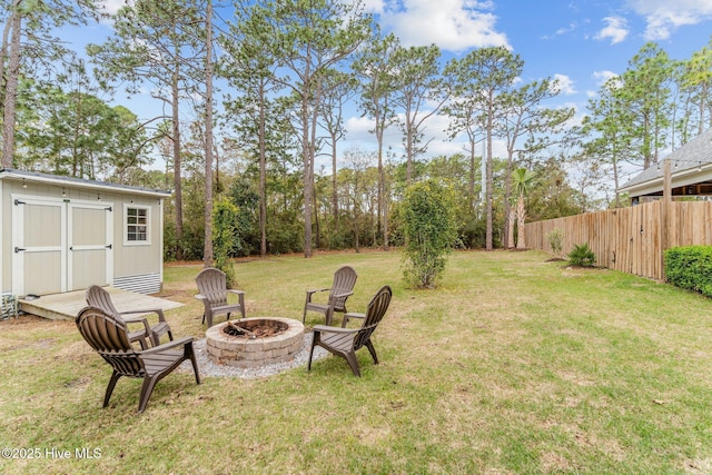 view of yard featuring a storage unit, fence, a fire pit, and an outdoor structure