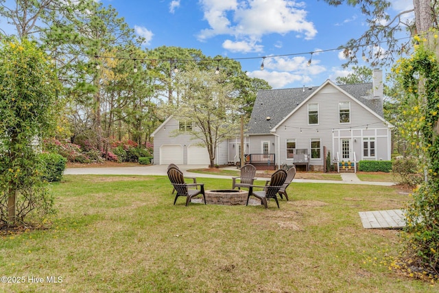 view of yard featuring a garage, a wooden deck, an outdoor structure, and an outdoor fire pit