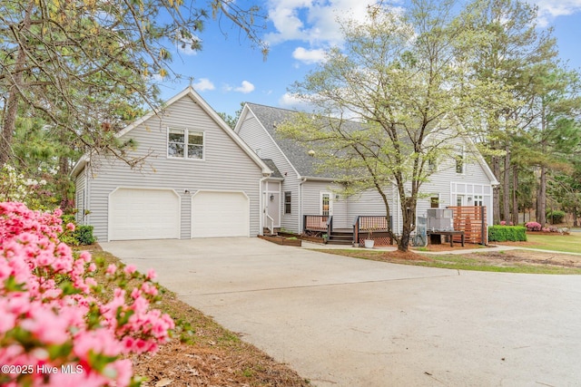 view of front of house featuring an attached garage, driveway, and a wooden deck