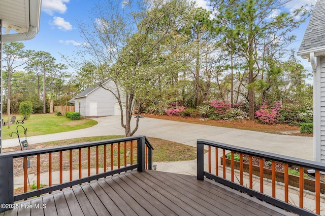 wooden deck with a yard, an outdoor structure, a garage, and concrete driveway