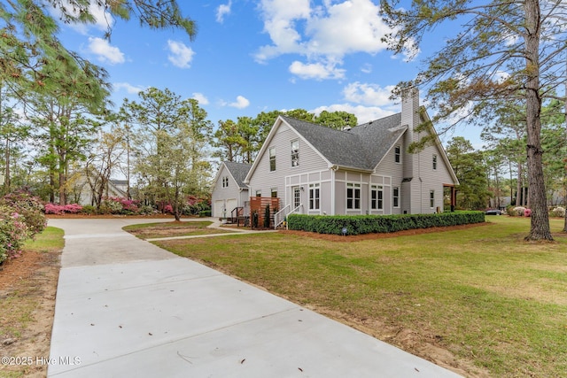 view of front of property featuring concrete driveway, a front yard, roof with shingles, and a chimney