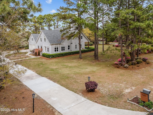 exterior space with concrete driveway, a shingled roof, a garage, and a front lawn