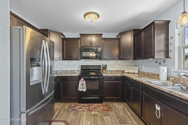 kitchen with light wood finished floors, backsplash, black appliances, and a sink