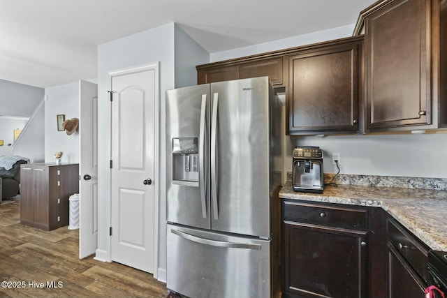 kitchen with dark wood-style floors, dark brown cabinetry, stainless steel refrigerator with ice dispenser, and light stone counters