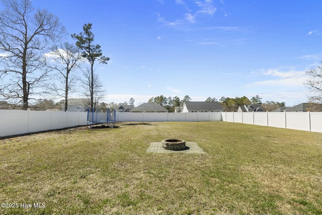 view of yard featuring an outdoor fire pit, a trampoline, and a fenced backyard
