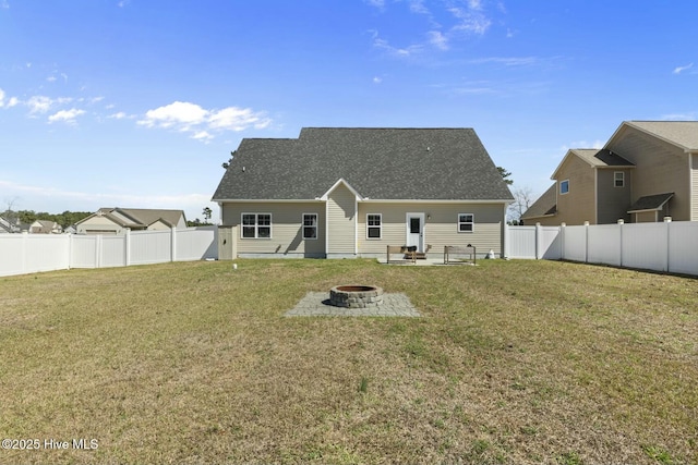 back of property with a fenced backyard, a fire pit, and a yard