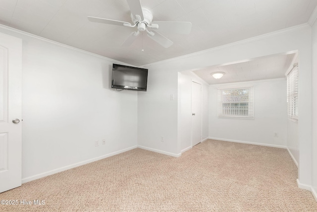 carpeted empty room with crown molding, baseboards, and ceiling fan