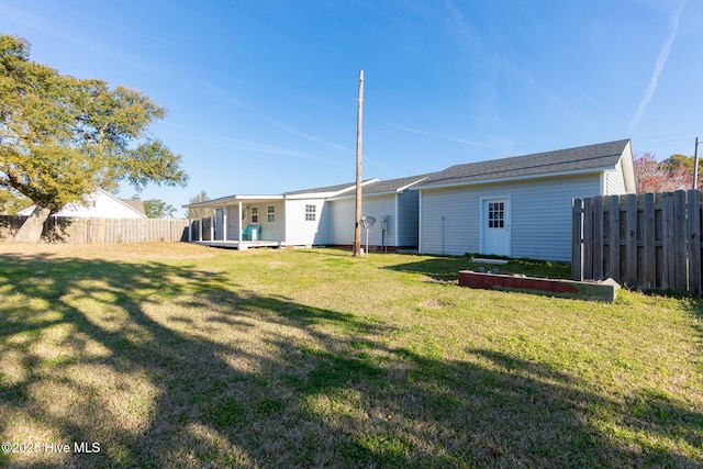 rear view of property featuring fence and a lawn