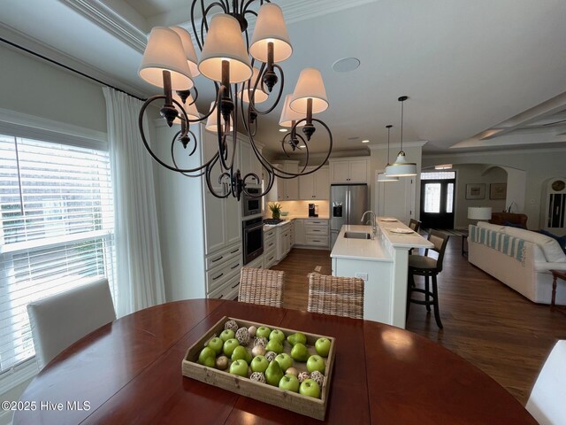 1325 Grandiflora Dr, Leland, NC 28451 - dining area with dark wood-style floors, arched walkways, ornamental molding, and a chandelier
