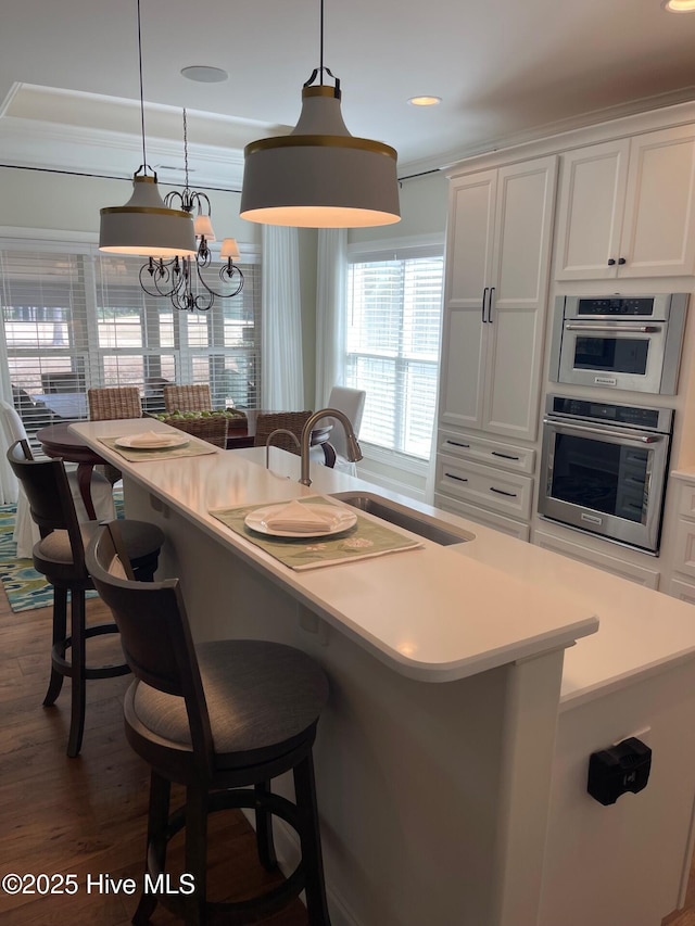 1325 Grandiflora Dr, Leland, NC 28451 - kitchen featuring white cabinetry, a breakfast bar, a sink, and dark wood-style flooring