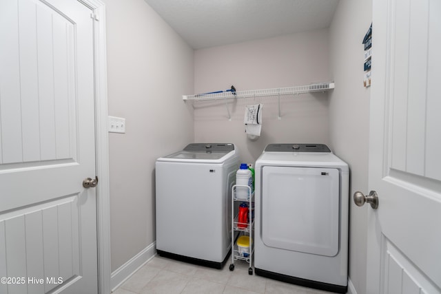 laundry area with washing machine and clothes dryer, light tile patterned floors, baseboards, and laundry area