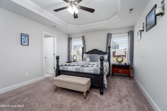 carpeted bedroom with a raised ceiling, ornamental molding, baseboards, and visible vents
