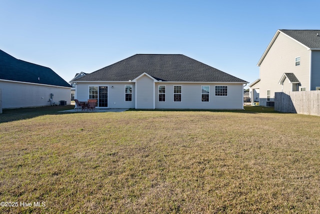 back of house featuring roof with shingles, fence, a patio area, and a lawn