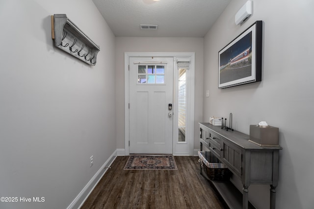 foyer with dark wood-style flooring, visible vents, baseboards, and a textured ceiling