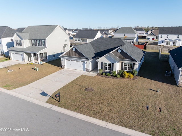 view of front of property with fence, an attached garage, stone siding, a residential view, and driveway