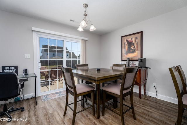 dining room with baseboards, visible vents, a notable chandelier, and wood finished floors