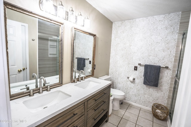 bathroom featuring toilet, wallpapered walls, a sink, and tile patterned floors