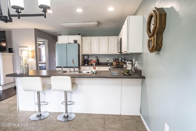 kitchen with freestanding refrigerator, stainless steel microwave, a sink, and dark countertops
