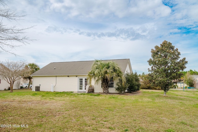 view of side of home with a shingled roof, cooling unit, french doors, and a yard