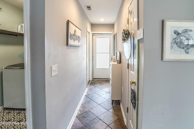 hall with baseboards, washer / clothes dryer, visible vents, and stone tile floors
