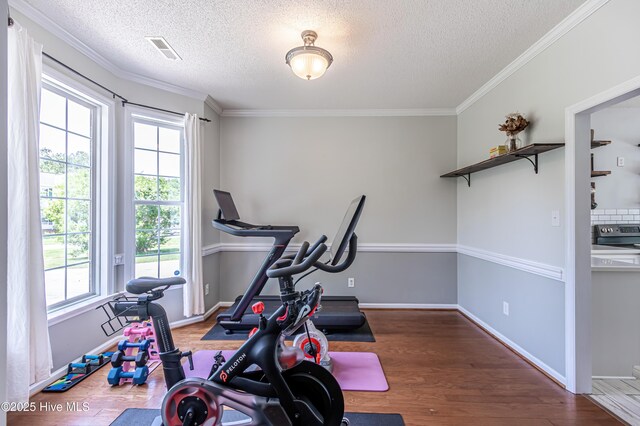 exercise room with a wealth of natural light, a textured ceiling, and visible vents