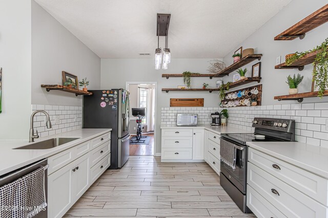 kitchen featuring open shelves, decorative backsplash, light countertops, a sink, and stainless steel appliances