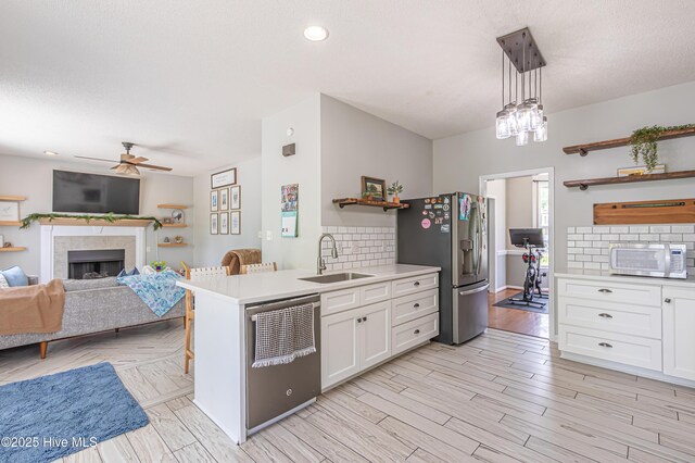 kitchen with light countertops, open shelves, a sink, and stainless steel appliances