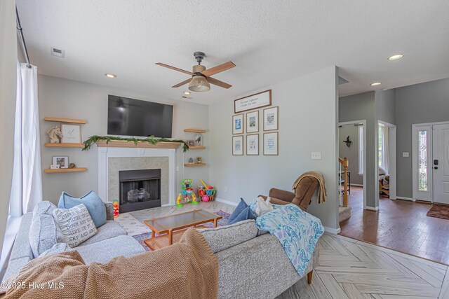 living room featuring ceiling fan, recessed lighting, a tile fireplace, visible vents, and stairway