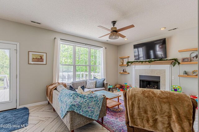 living room featuring ceiling fan, visible vents, a wealth of natural light, and a fireplace