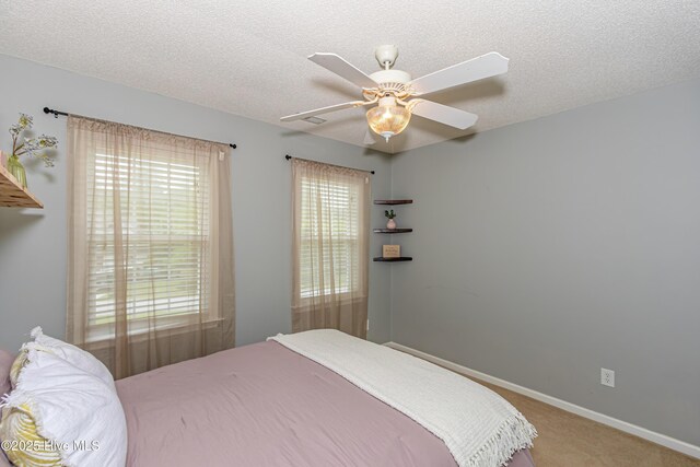 bedroom with carpet floors, a textured ceiling, ceiling fan, and baseboards