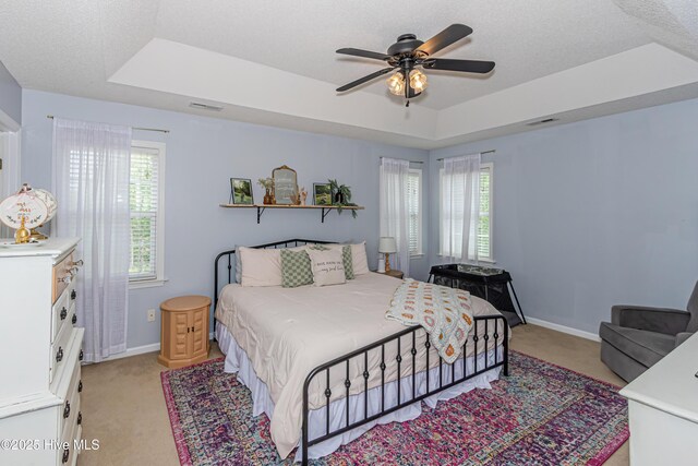 bedroom with a raised ceiling, baseboards, light carpet, and visible vents