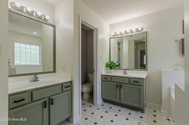 full bath with a garden tub, tile patterned flooring, toilet, two vanities, and a sink