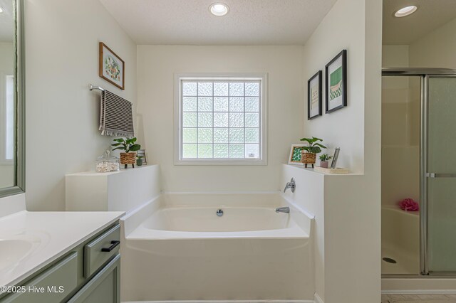 full bath with vanity, recessed lighting, a textured ceiling, a bath, and a shower stall