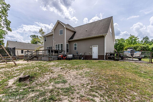 back of house featuring fence, a deck, roof with shingles, a lawn, and central air condition unit