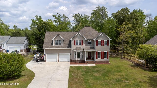 traditional-style house with fence, a shingled roof, a garage, a front yard, and concrete driveway
