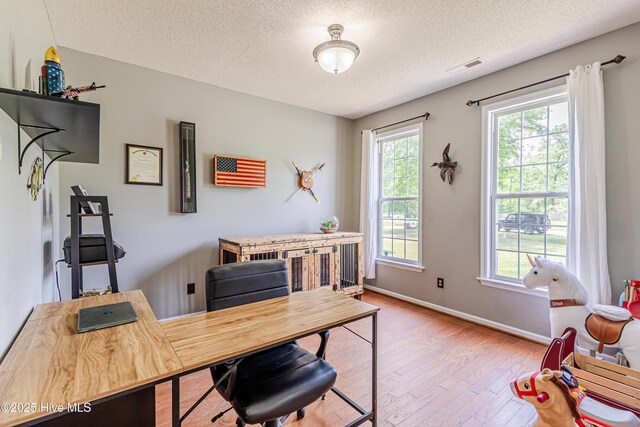 home office featuring a textured ceiling, visible vents, baseboards, and hardwood / wood-style floors