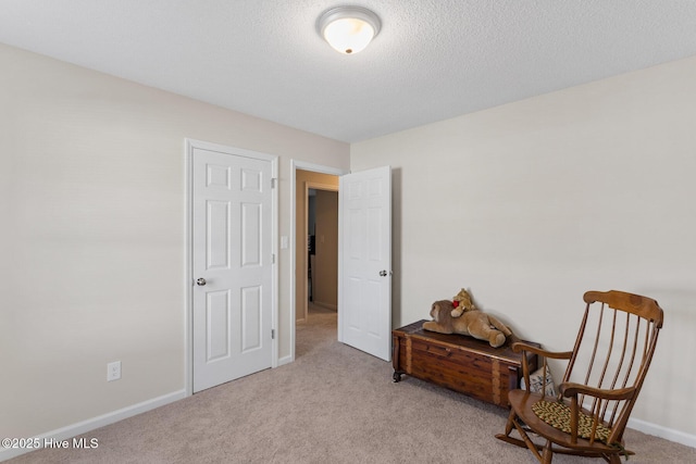 living area featuring baseboards, carpet, and a textured ceiling