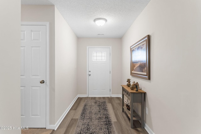entryway with baseboards, a textured ceiling, and wood finished floors