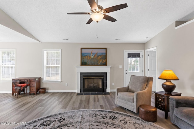 living room with visible vents, wood finished floors, a ceiling fan, and plenty of natural light