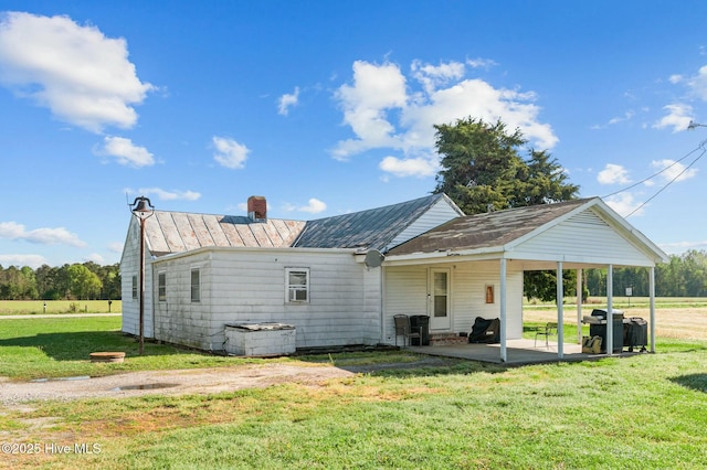 5635 Mckendree Church Rd, Tarboro, NC 27886 - rear view of house with a chimney, a patio area, a standing seam roof, metal roof, and a lawn