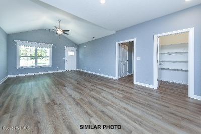 interior space with baseboards, lofted ceiling, wood finished floors, and a ceiling fan