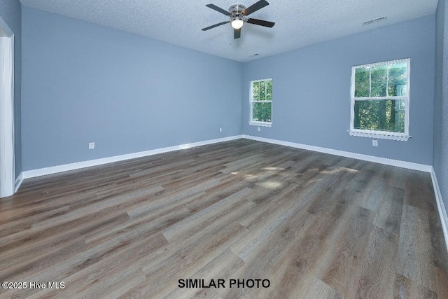 empty room featuring baseboards, a textured ceiling, visible vents, a ceiling fan, and wood finished floors