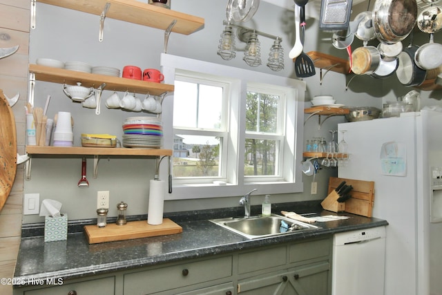 kitchen featuring a sink, open shelves, green cabinets, white appliances, and dark countertops