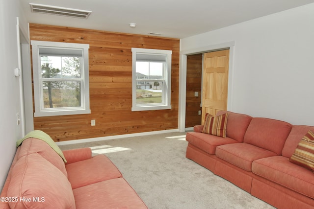carpeted living room with wood walls, baseboards, and visible vents