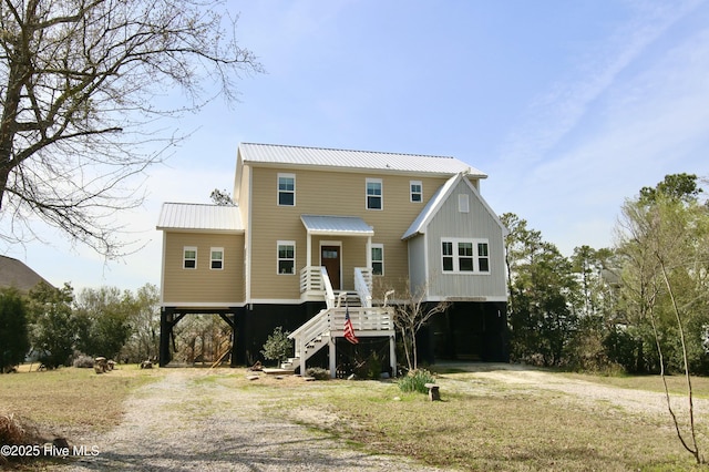beach home featuring dirt driveway, metal roof, stairway, and a carport