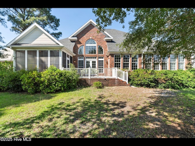 4404 Gauntlet Dr SE, Southport, NC 28461 - back of property with brick siding, a sunroom, a yard, roof with shingles, and a deck