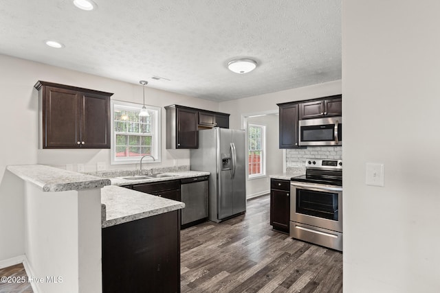 kitchen featuring dark brown cabinets, stainless steel appliances, a sink, and plenty of natural light