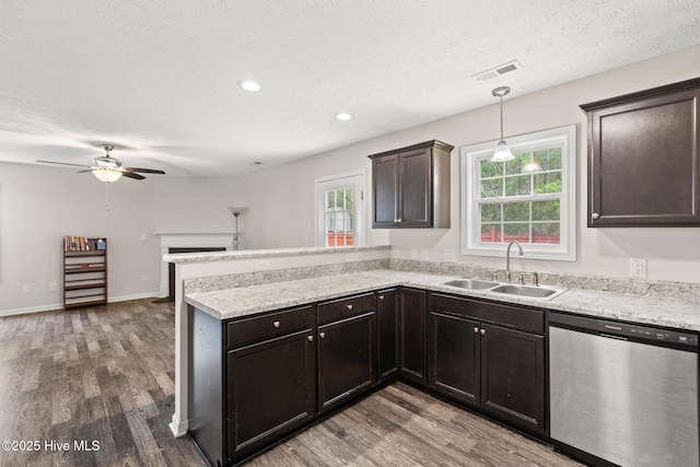 kitchen with a peninsula, dishwasher, wood finished floors, and a sink