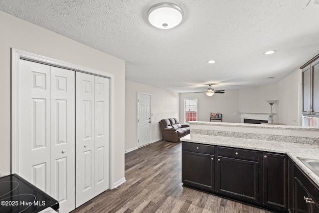 kitchen featuring recessed lighting, dark wood-type flooring, a fireplace, open floor plan, and ceiling fan